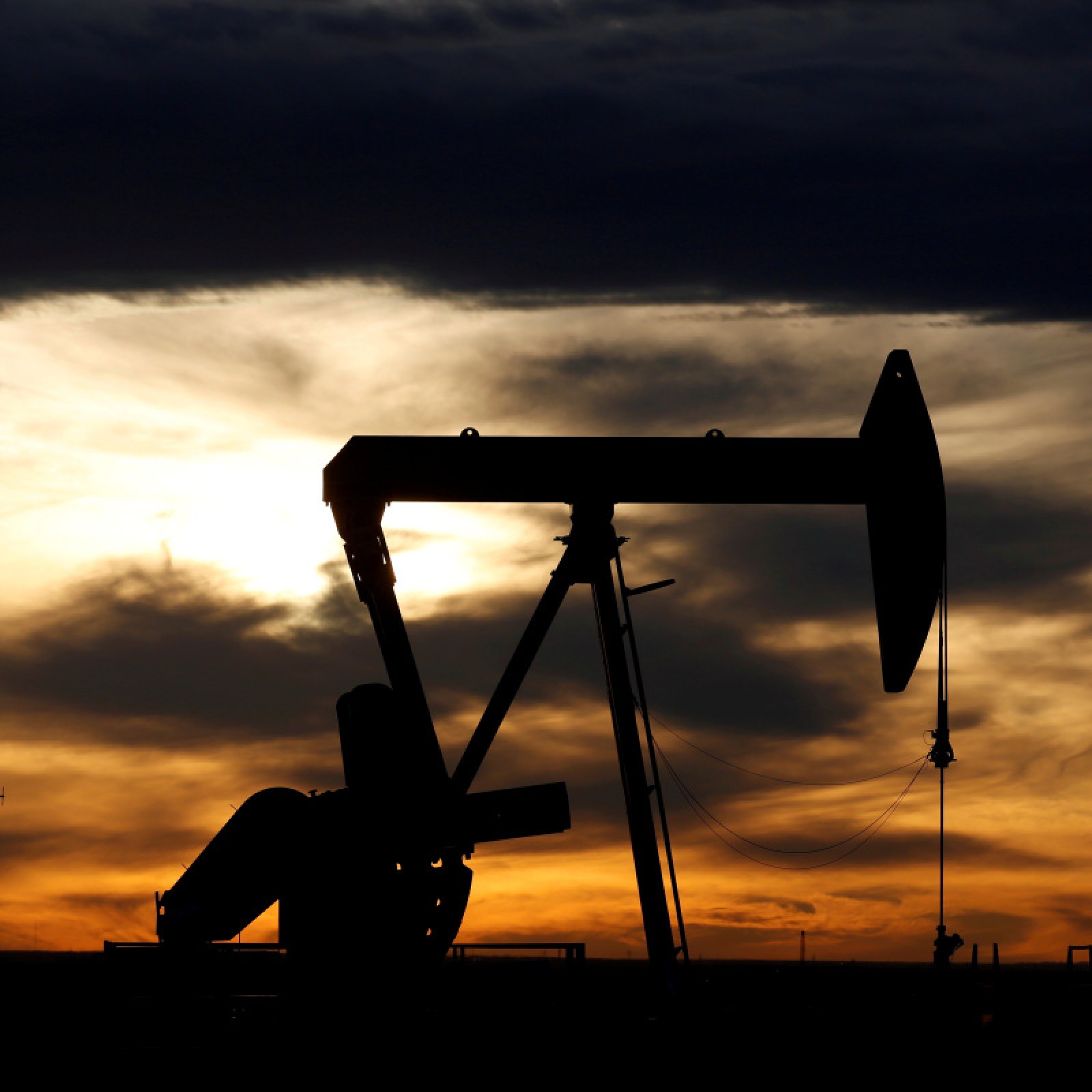 The sun sets behind a crude oil pump jack on a drill pad in the Permian Basin in Loving County