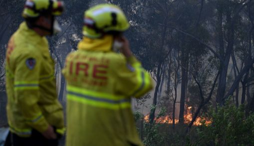 NSW Rural Fire Service and Fire and Rescue NSW personnel conduct property protection as a bushfire burns in Woodford NSW