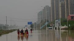 Rescue workers help people cross a flooded street after heavy rain that flooded the city of Zhengzhou
