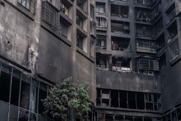 The exterior walls of a residential building stands charred in the wake of a fire