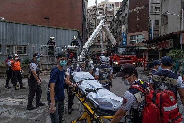 Paramedics transporting a dead body from a residential building in the wake of a fire